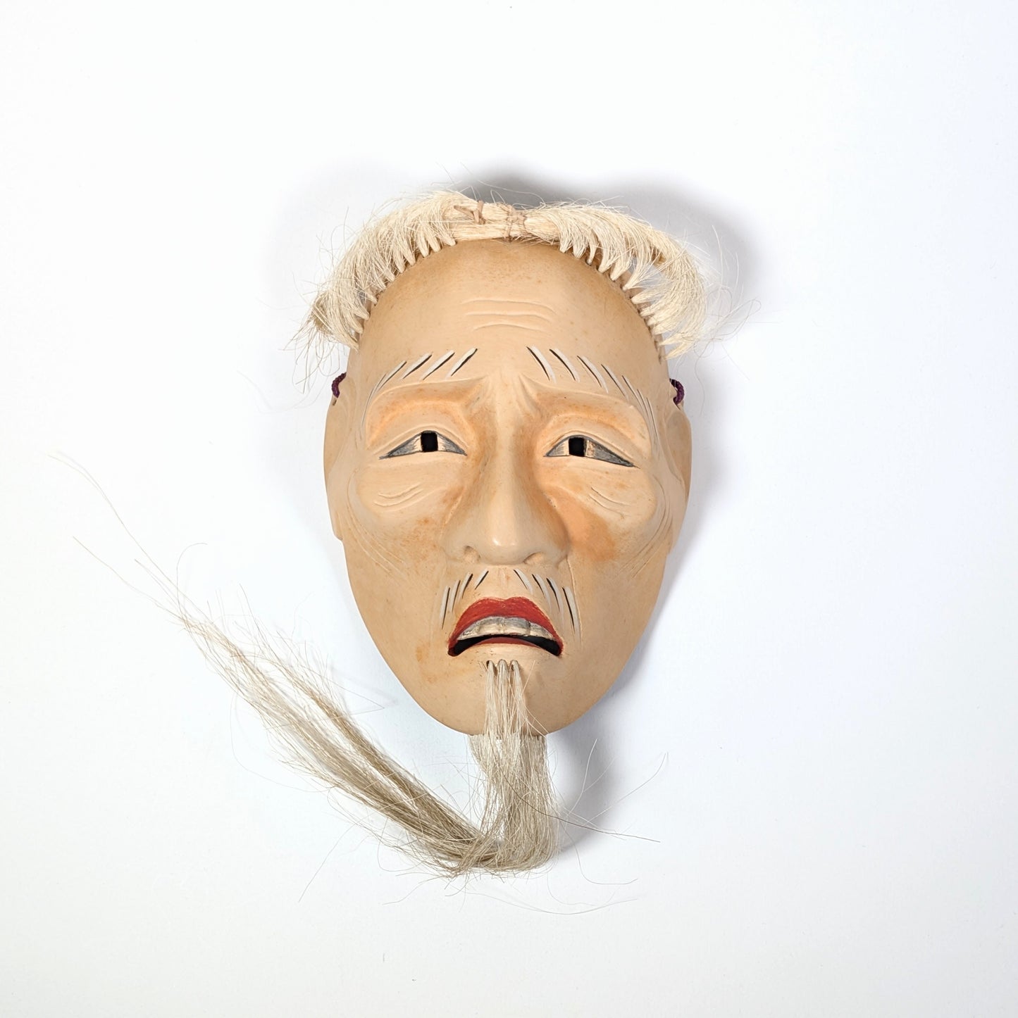 Masque de Nô japonais Kōshi-jō vu de face sous une lumière douce, révélant une expression calme et digne.
