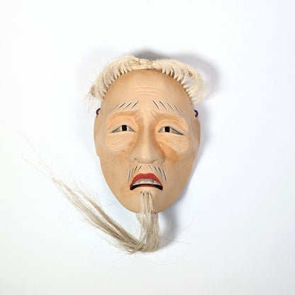 Masque de Nô japonais Kōshi-jō vu de face sous une lumière douce, révélant une expression calme et digne.
