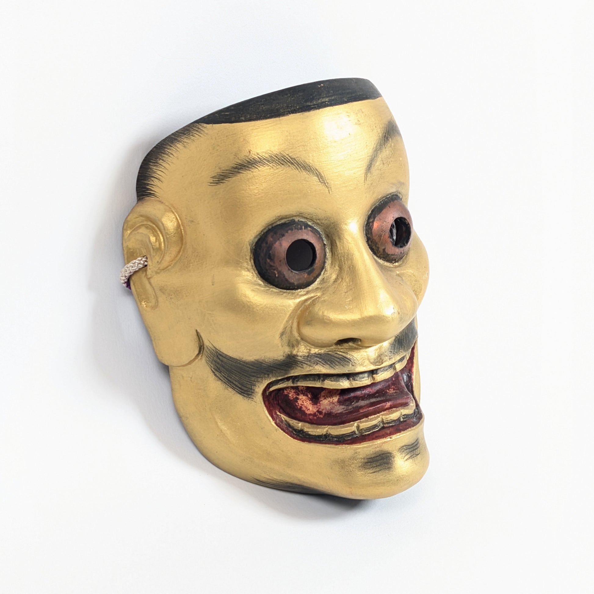 Vue trois-quarts d’un masque japonais traditionnel Ōtobide aux yeux globuleux et à la bouche ouverte