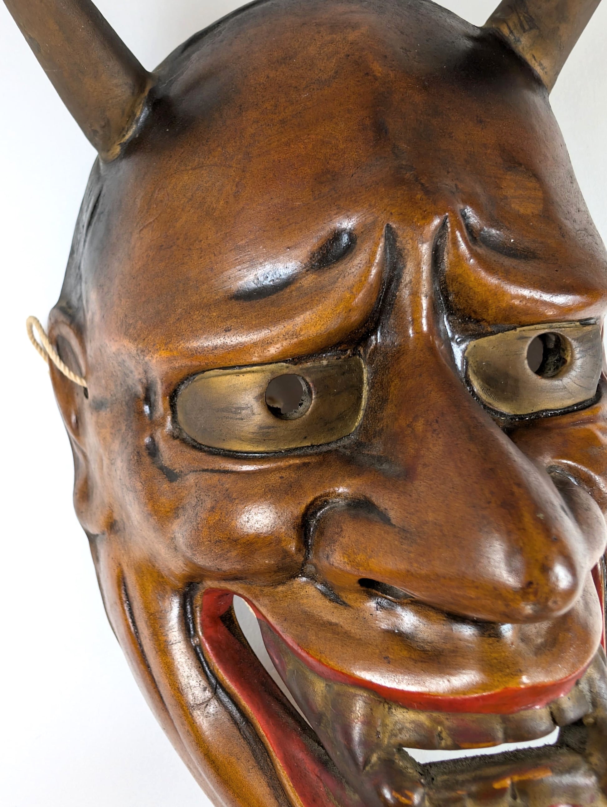 Détail du visage d’un masque Nô japonais : cornes, yeux et expression intensifiée par la lumière