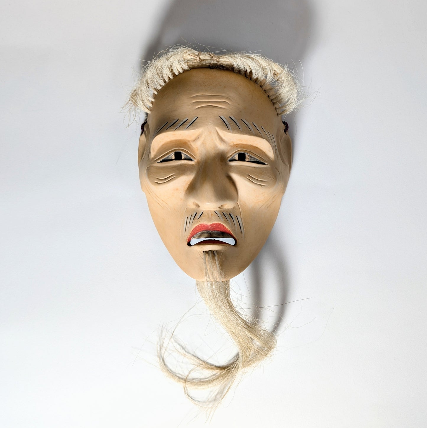 Masque de Nô japonais représentant un vieillard, nōmen ancien dont l’expression devient dramatique selon la lumière.