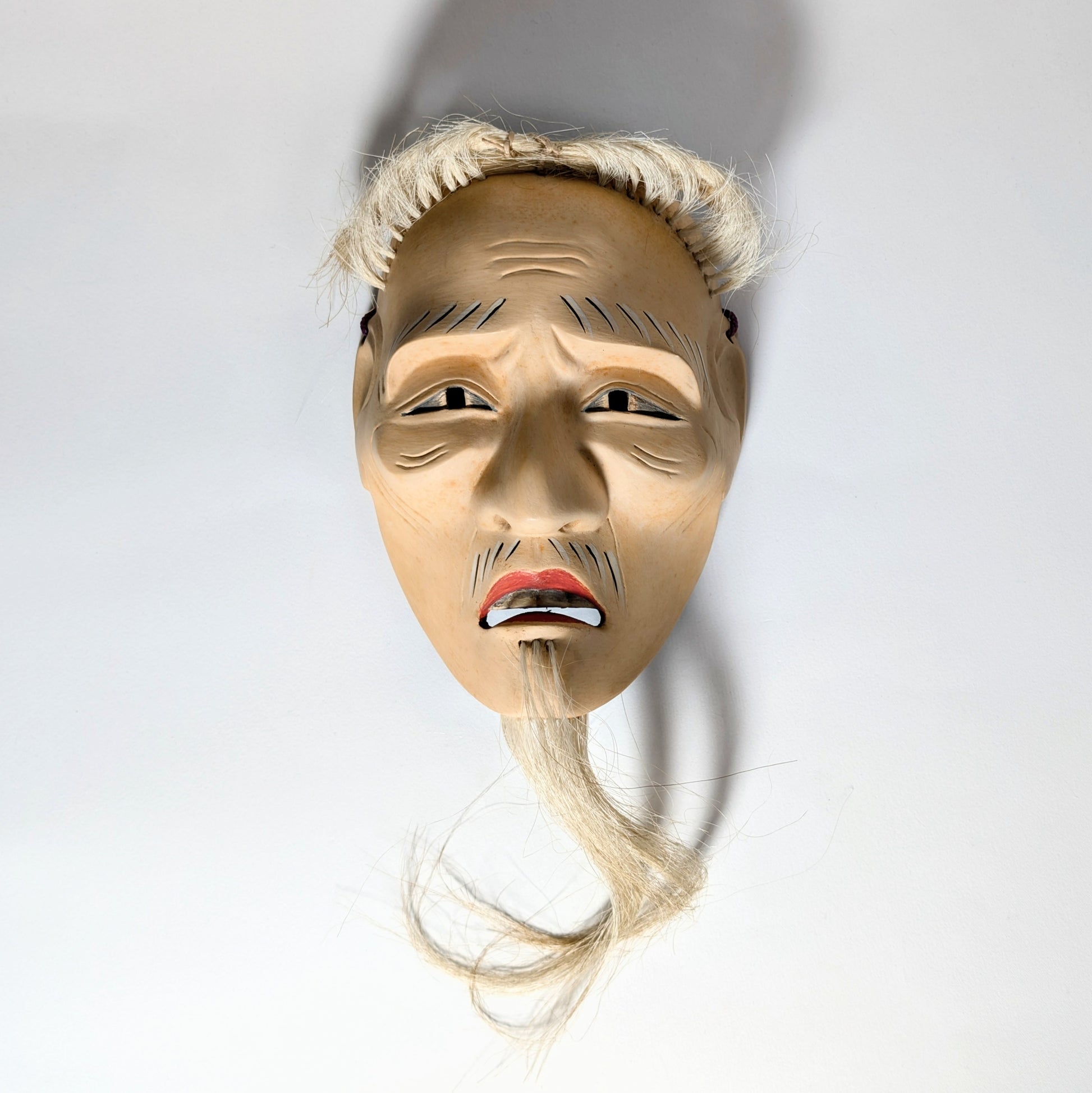 Masque de Nô japonais représentant un vieillard, nōmen ancien dont l’expression devient dramatique selon la lumière.