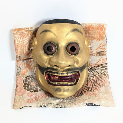 Masque Nô japonais Ōtobide 大飛出 en bois sculpté et doré présenté sur sa pochette traditionnelle en soie japonaise