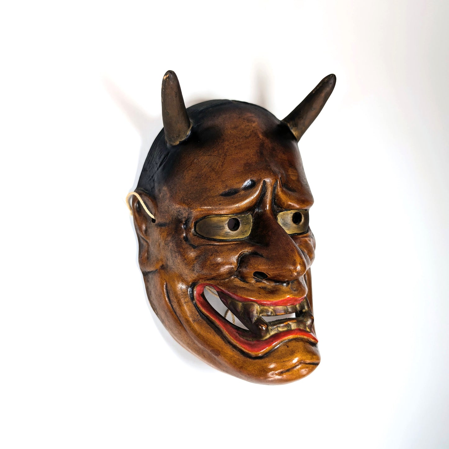 Vue de profil d’un masque de théâtre Nô japonais ancien avec cornes, lumière latérale douce