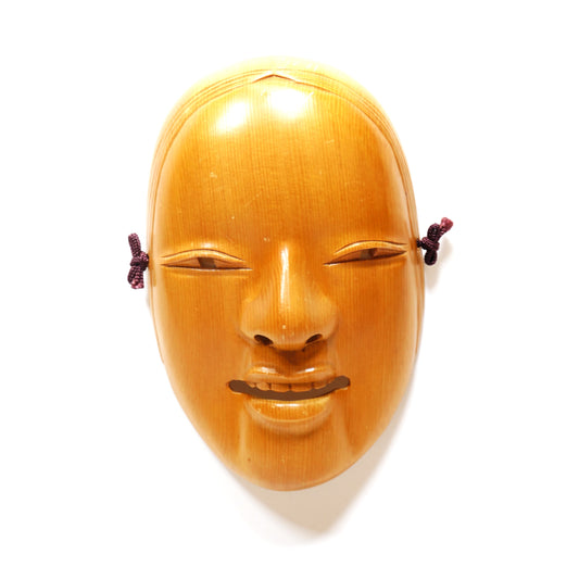 Masque Nō Ko-Omote avec éclairage venant du haut représentant une jeune femme japonaise souriante en bois sculpté