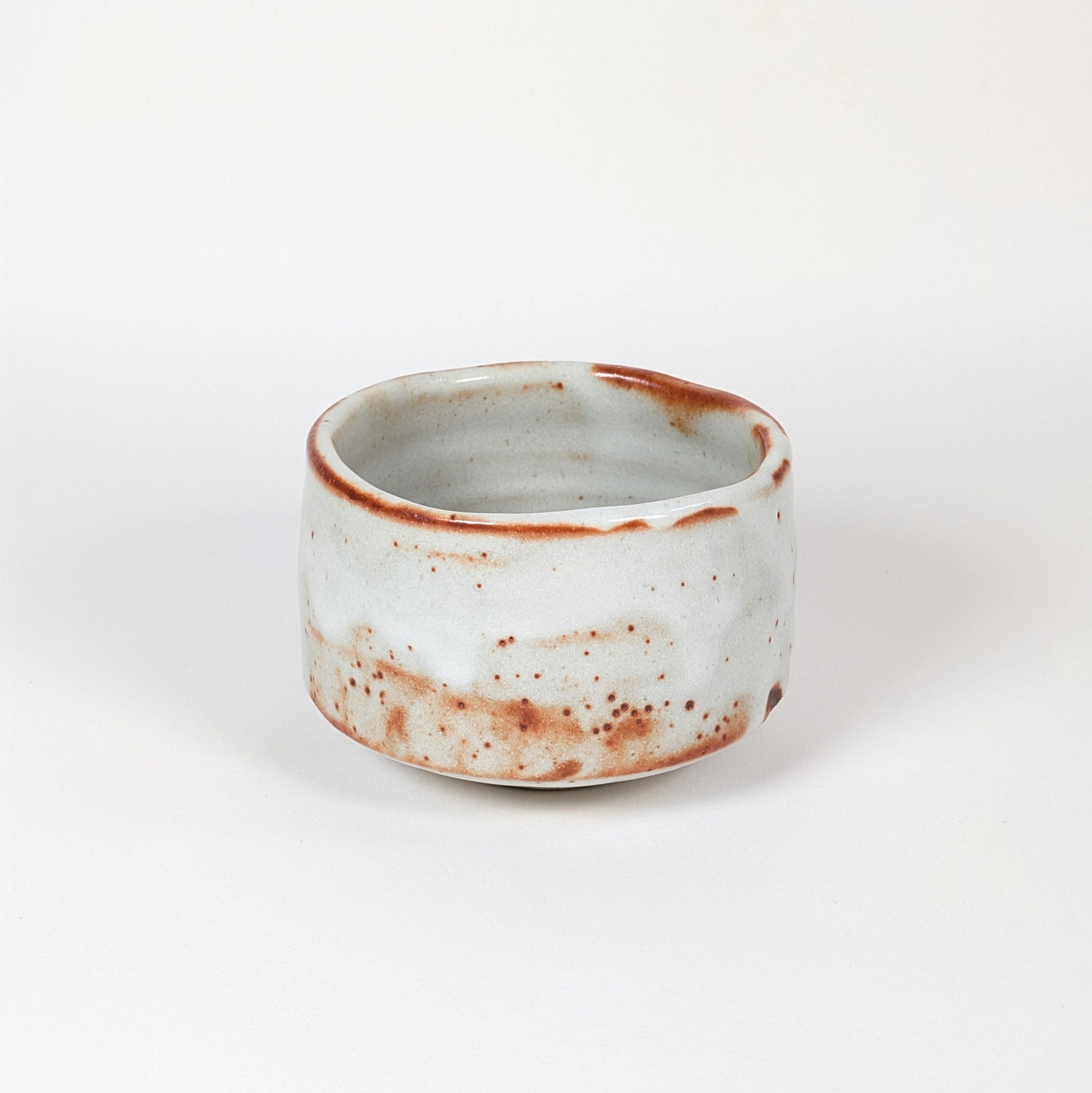 Matchawan japonais Beni Shino, bol de cérémonie du thé à glaçure blanche mouchetée, marques rouges de cuisson et forme basse traditionnelle.