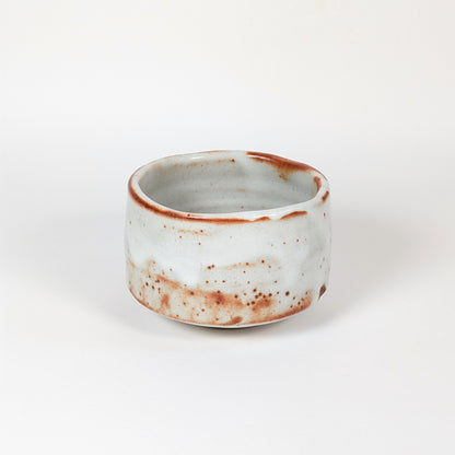 Matchawan japonais Beni Shino, bol de cérémonie du thé à glaçure blanche mouchetée, marques rouges de cuisson et forme basse traditionnelle.
