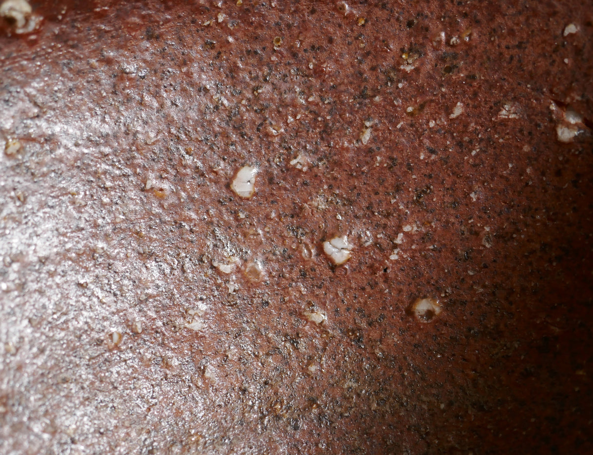 Gros plan intérieur du chawan Shigaraki révélant la terre ferrugineuse, les grains de feldspath et les effets ishihaze