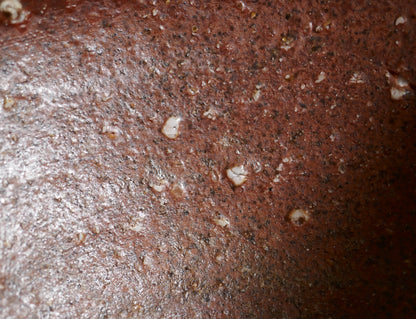 Gros plan intérieur du chawan Shigaraki révélant la terre ferrugineuse, les grains de feldspath et les effets ishihaze