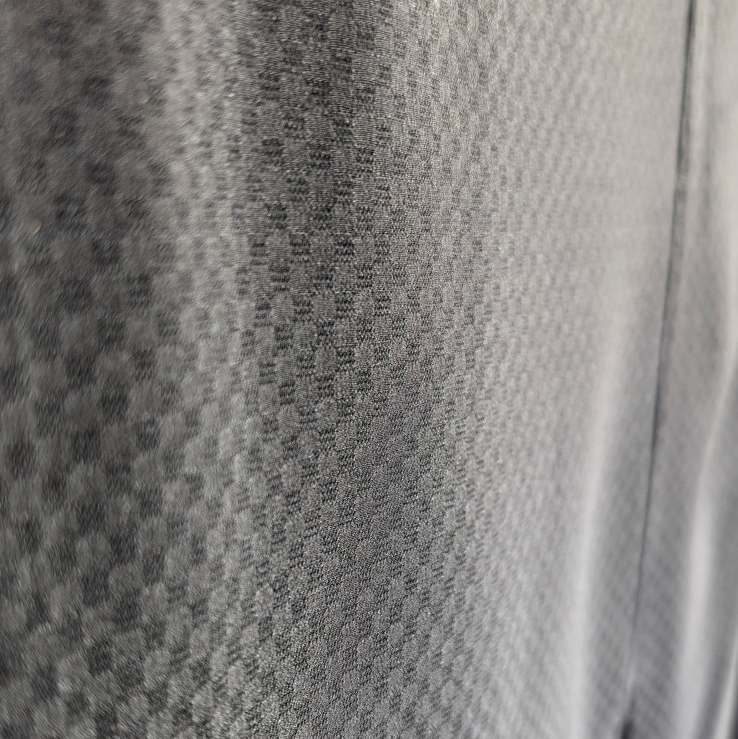 Gros plan du monsha ichimatsu en soie noire, tissage sha fin et ajouré révélant la transparence du damier japonais.