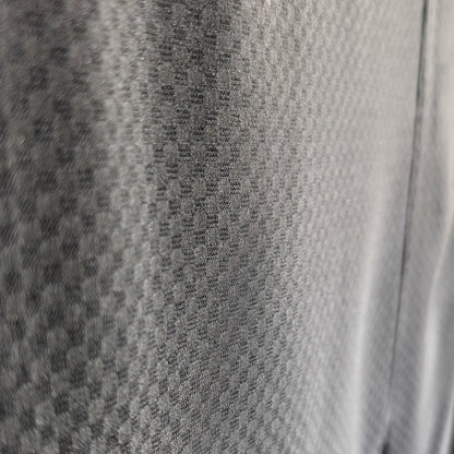 Gros plan du monsha ichimatsu en soie noire, tissage sha fin et ajouré révélant la transparence du damier japonais.