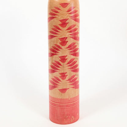 Détail du motif kasane-giku de la kokeshi traditionnelle, composé de chrysanthèmes superposés rouges sur bois naturel.
