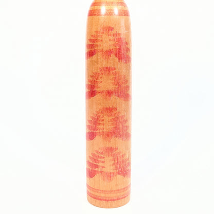 Détail du motif kasanegiku sur le corps d’une kokeshi Togatta, chrysanthèmes superposés rouges peints sur bois naturel verni.