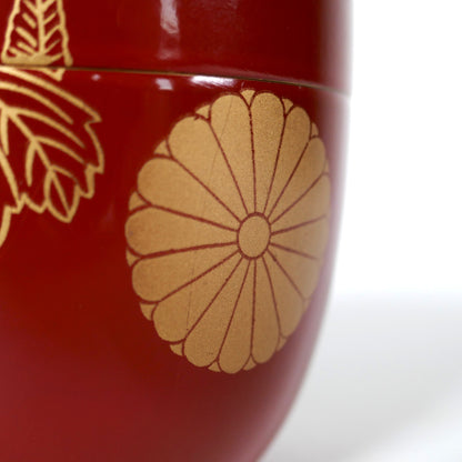 Gros plan sur le motif kiku, chrysanthème doré sur boîte japonaise natsume en laque rouge brillante avec décor maki-e