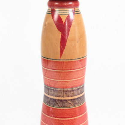Détail du motif de kimono rouge et jaunes et des bandes peintes au tour d’une kokeshi Yajiro japonaise des années 1970
