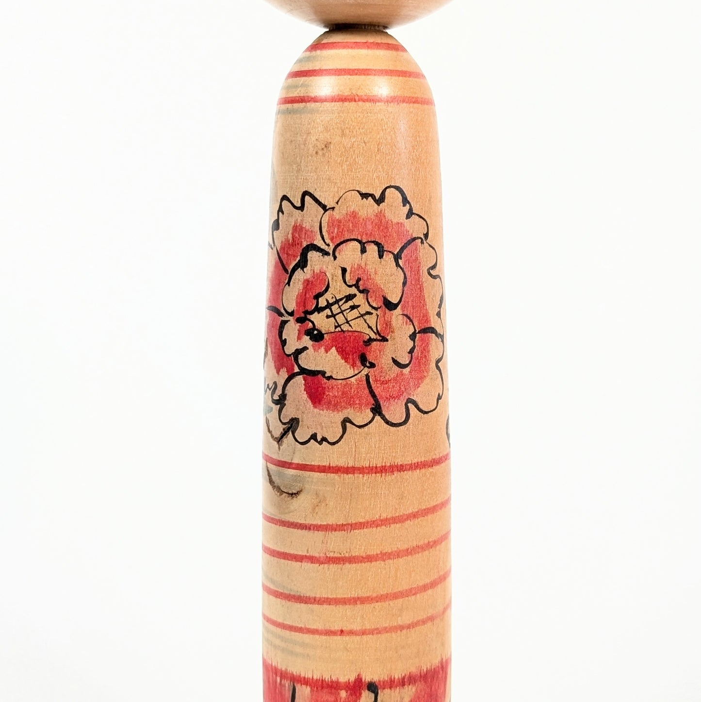 Motif pivoine botan peint à la main sur le corps d’une kokeshi traditionnelle japonaise.