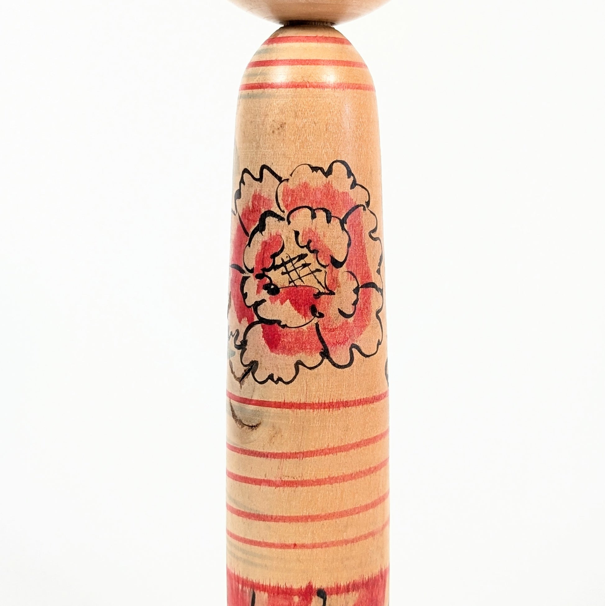 Motif pivoine botan peint à la main sur le corps d’une kokeshi traditionnelle japonaise.