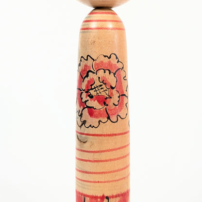 Motif pivoine botan peint à la main sur le corps d’une kokeshi traditionnelle japonaise.
