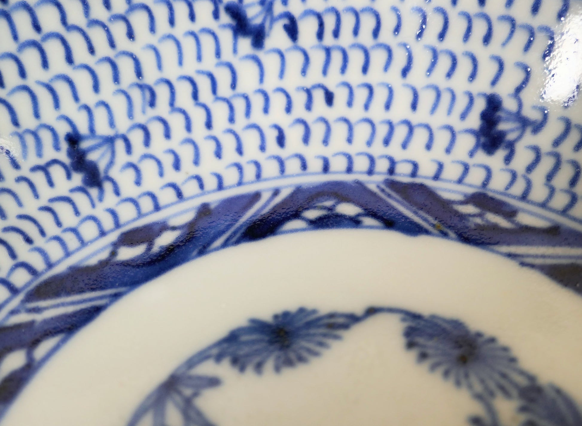Détail du motif mijin-karakusa peint en bleu cobalt sur une assiette japonaise Imari ancienne