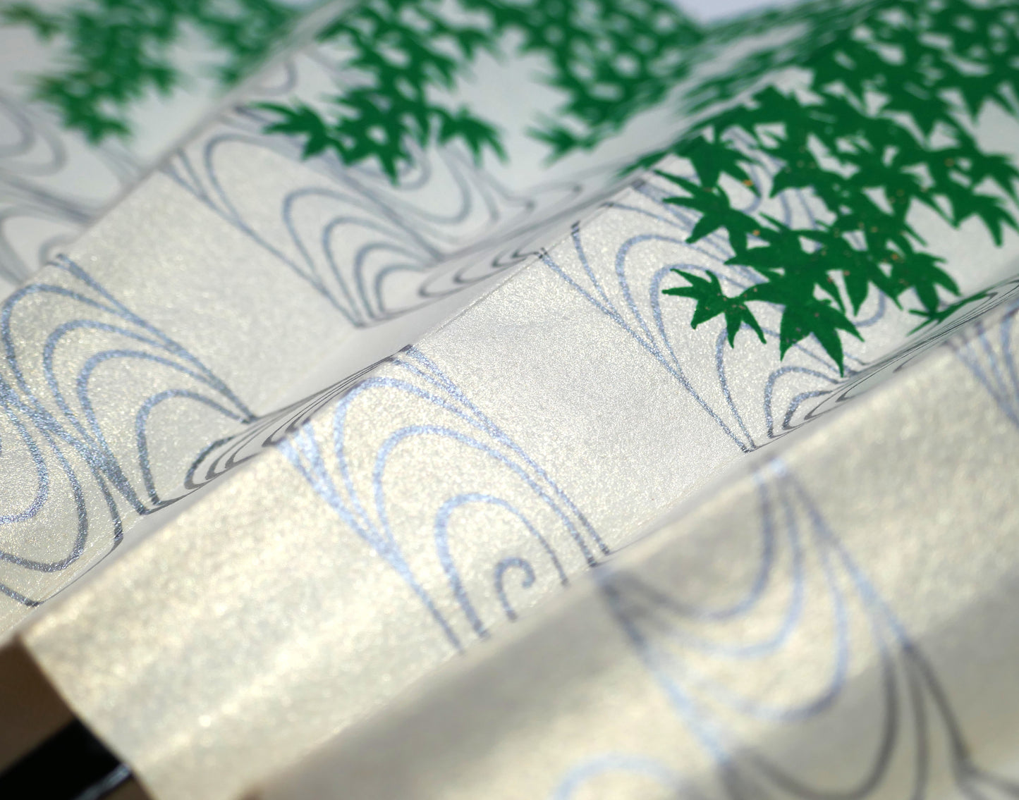 Détail du motif japonais ryūsui représentant une eau courante argentée parmi des feuilles d’érable vert.