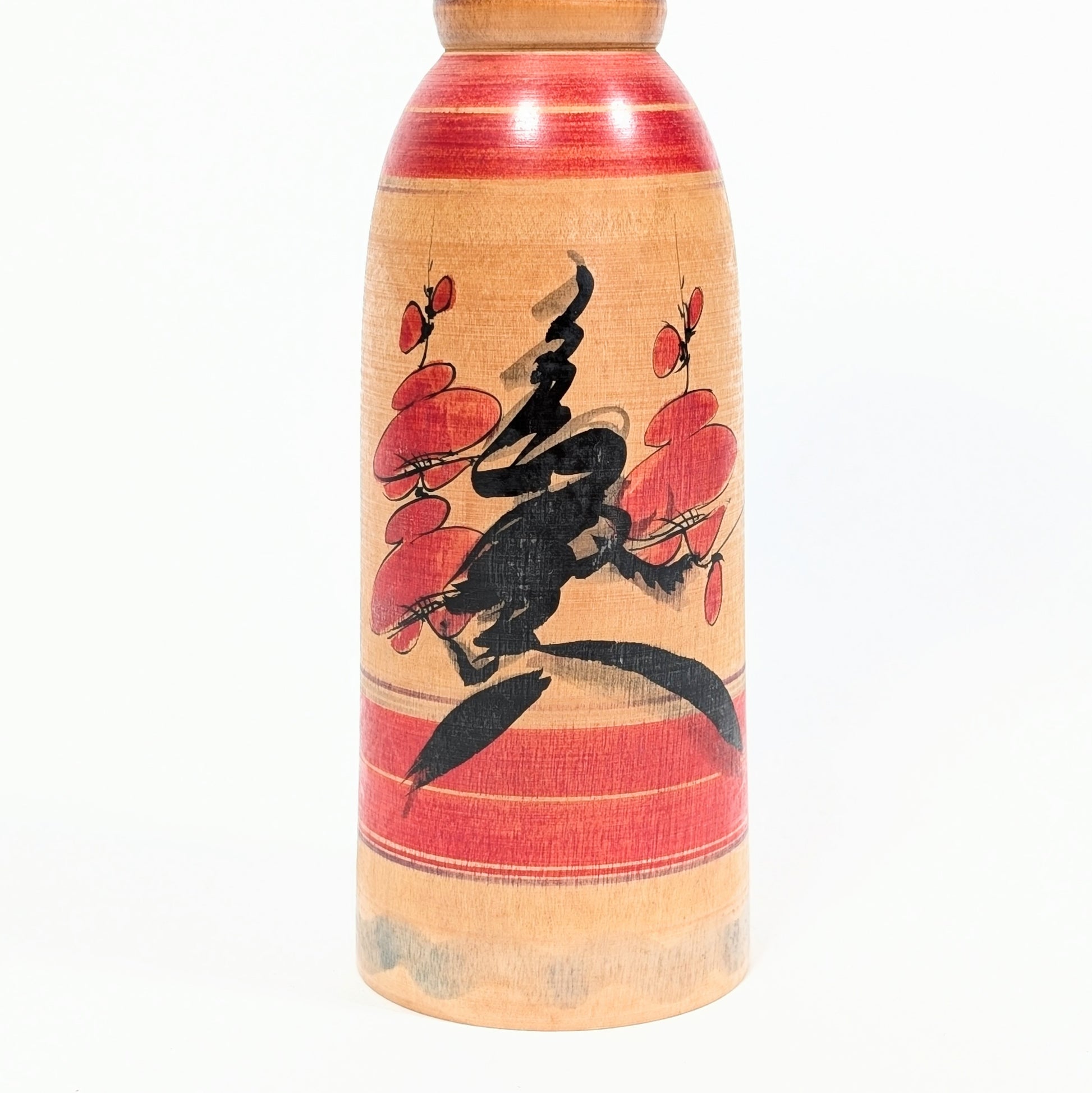 Détail du motif ume sur une kokeshi Yajirō, branches et fleurs de prunier peintes en rouge et noir sur bois naturel