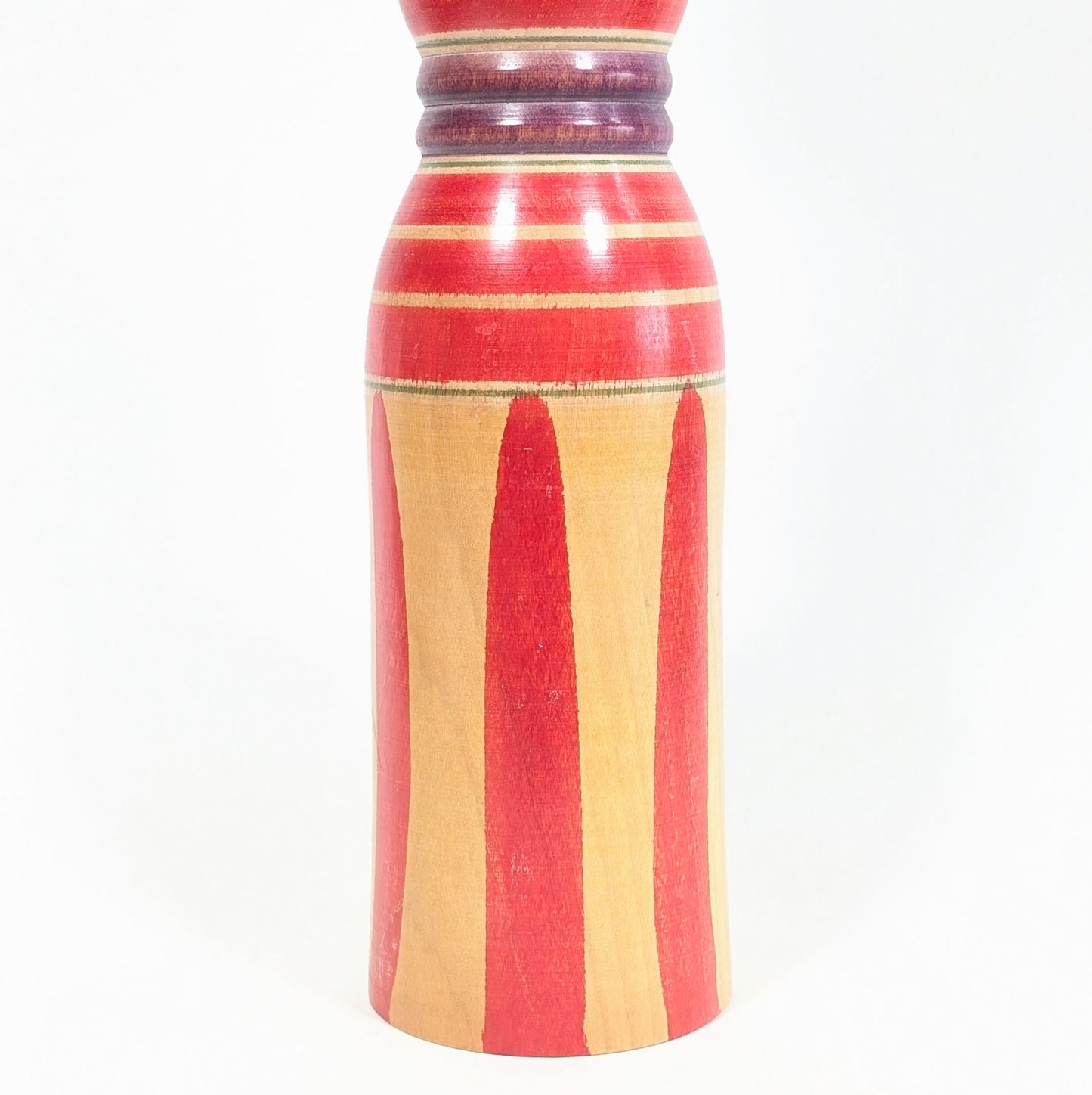 Motifs du corps d’une kokeshi Yajirō, longues rayures rouges sur bois naturel, décor graphique traditionnel de l’art populaire japonais