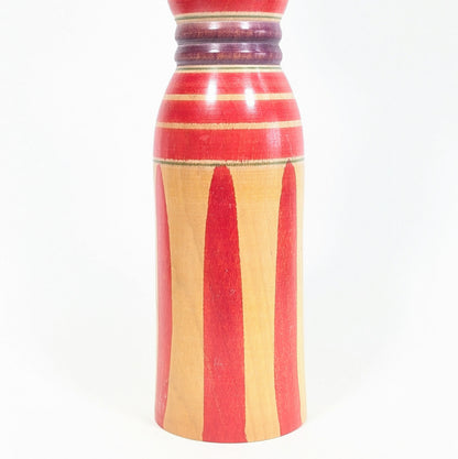 Motifs du corps d’une kokeshi Yajirō, longues rayures rouges sur bois naturel, décor graphique traditionnel de l’art populaire japonais