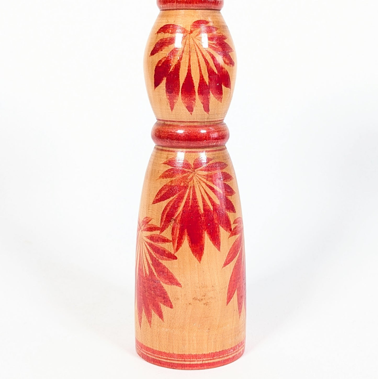 Détail des motifs hishigiku 菱菊, chrysanthèmes rouges peints sur le corps d’une kokeshi traditionnelle Yajirō