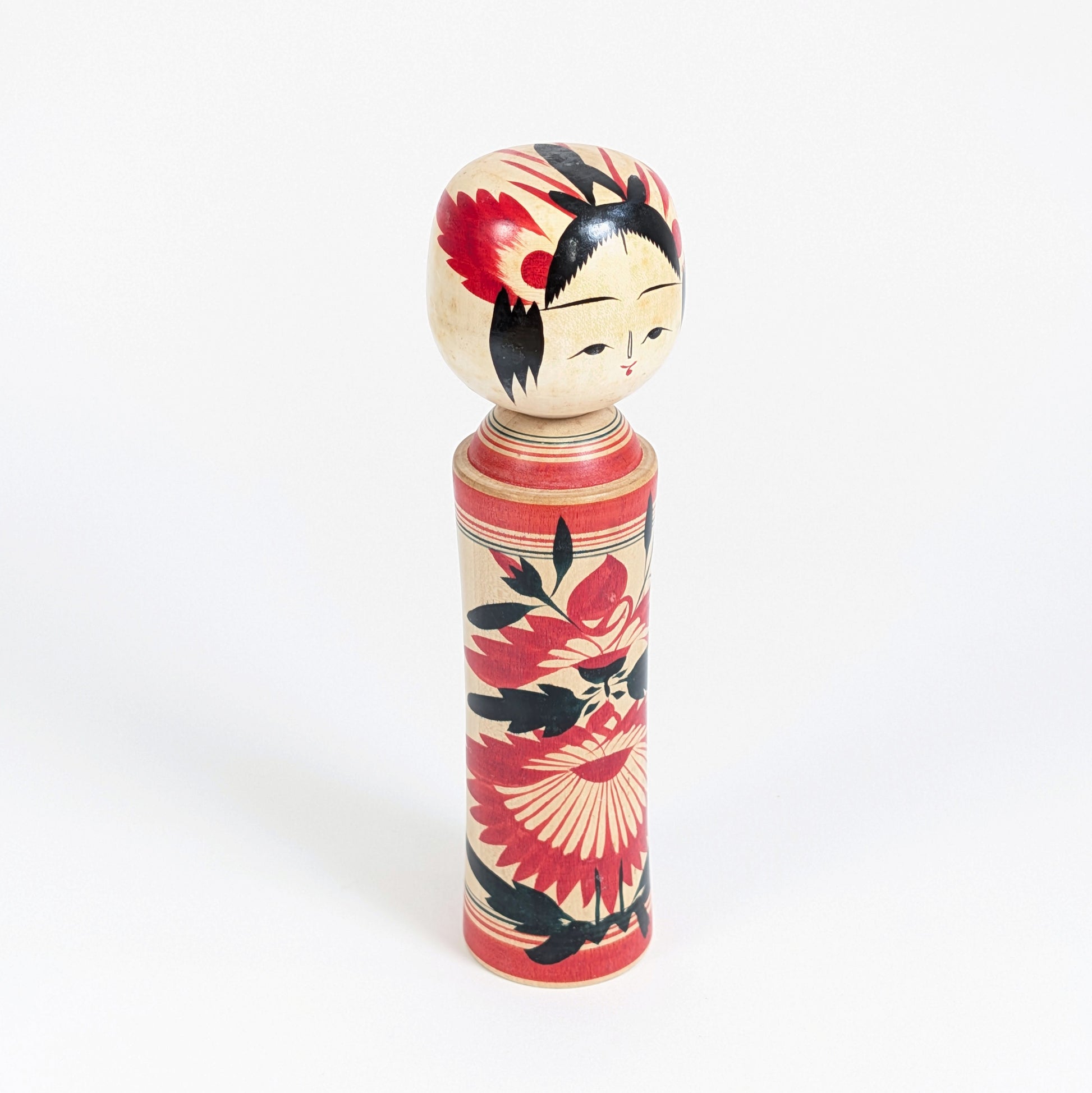 Vue trois-quarts d’une kokeshi Naruko-kei par Suzuki Toshiyuki, artisanat traditionnel japonais en bois peint à décor de chrysanthèmes.