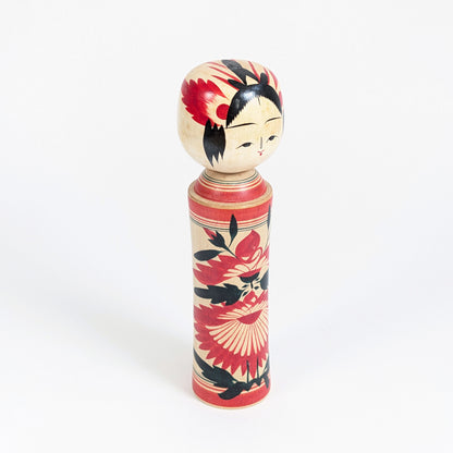 Vue trois-quarts d’une kokeshi Naruko-kei par Suzuki Toshiyuki, artisanat traditionnel japonais en bois peint à décor de chrysanthèmes.