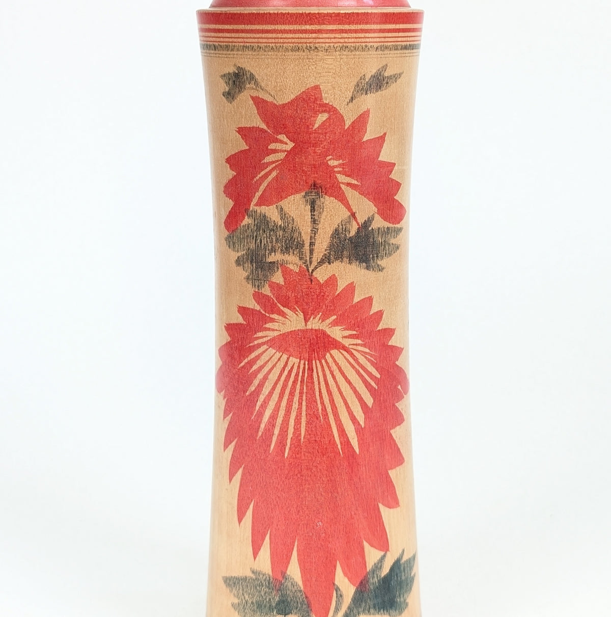 Détail du décor hishigiku 菱菊 sur une kokeshi Naruko, grand motif de chrysanthème rouge caractéristique de cet artisanat japonais.