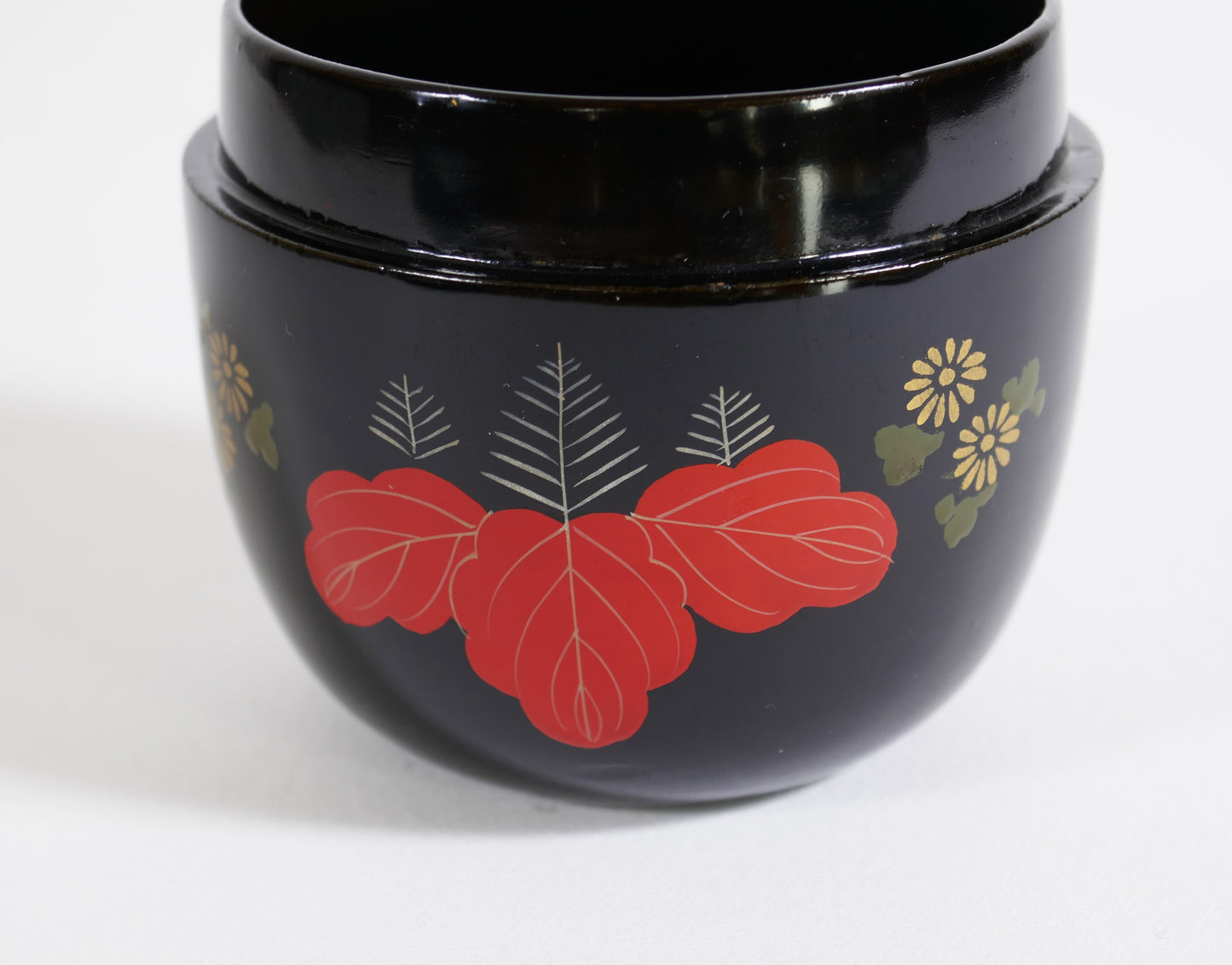 Gros plan sur un motif de feuille de paulownia rouge sur boîte à thé japonaise en laque noire