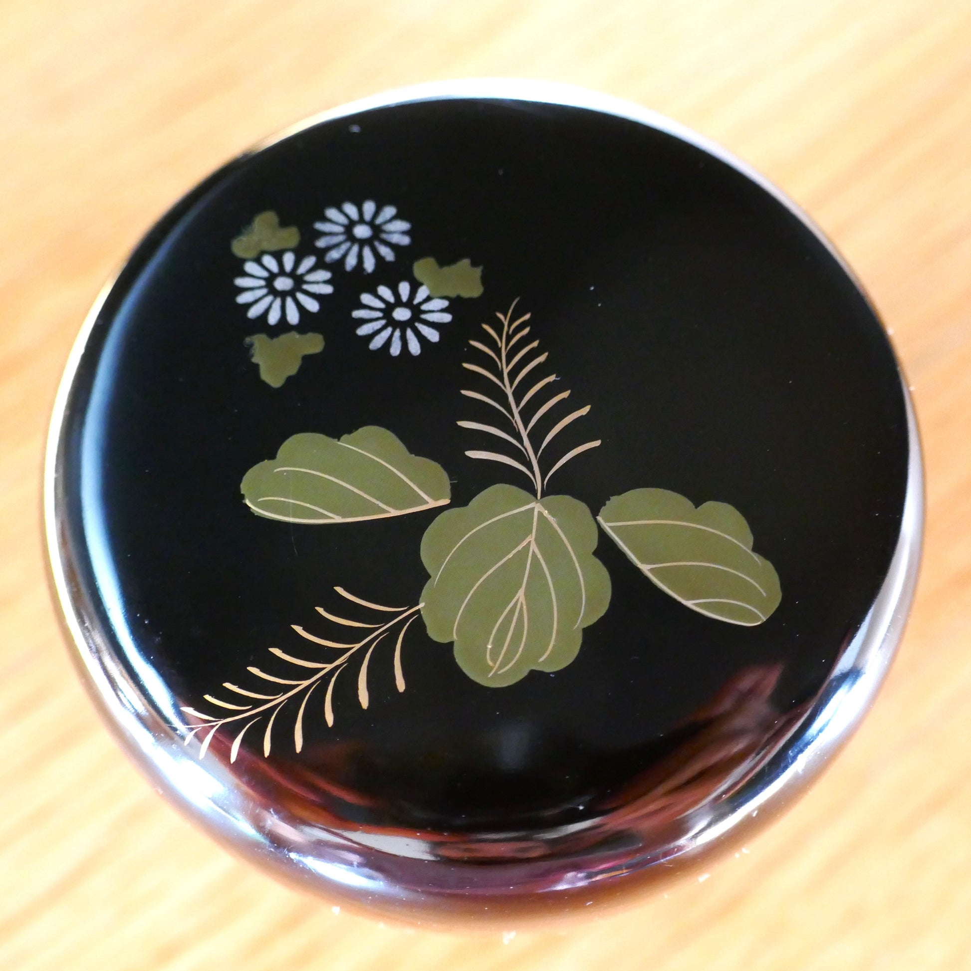 Couvercle de natsume en laque noire, décoré de feuilles de paulownia vertes et fleurs de chrysanthème stylisées