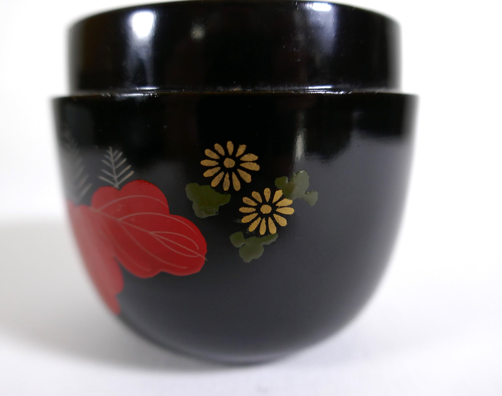 Détail rapproché d’un chrysanthème doré sur une boîte à thé japonaise en bois laqué noir