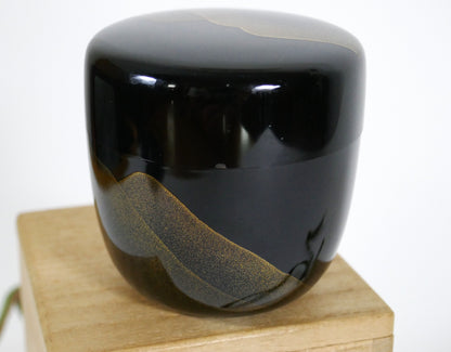 Natsume japonais en laque noire urushi avec motif de montagne dorée, posé sur sa boîte en bois signée. Micro éclat visible