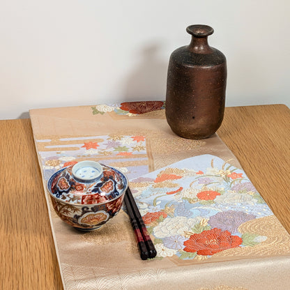 Fukuro obi japonais en soie et brocart doré présenté comme art textile avec céramiques japonaises