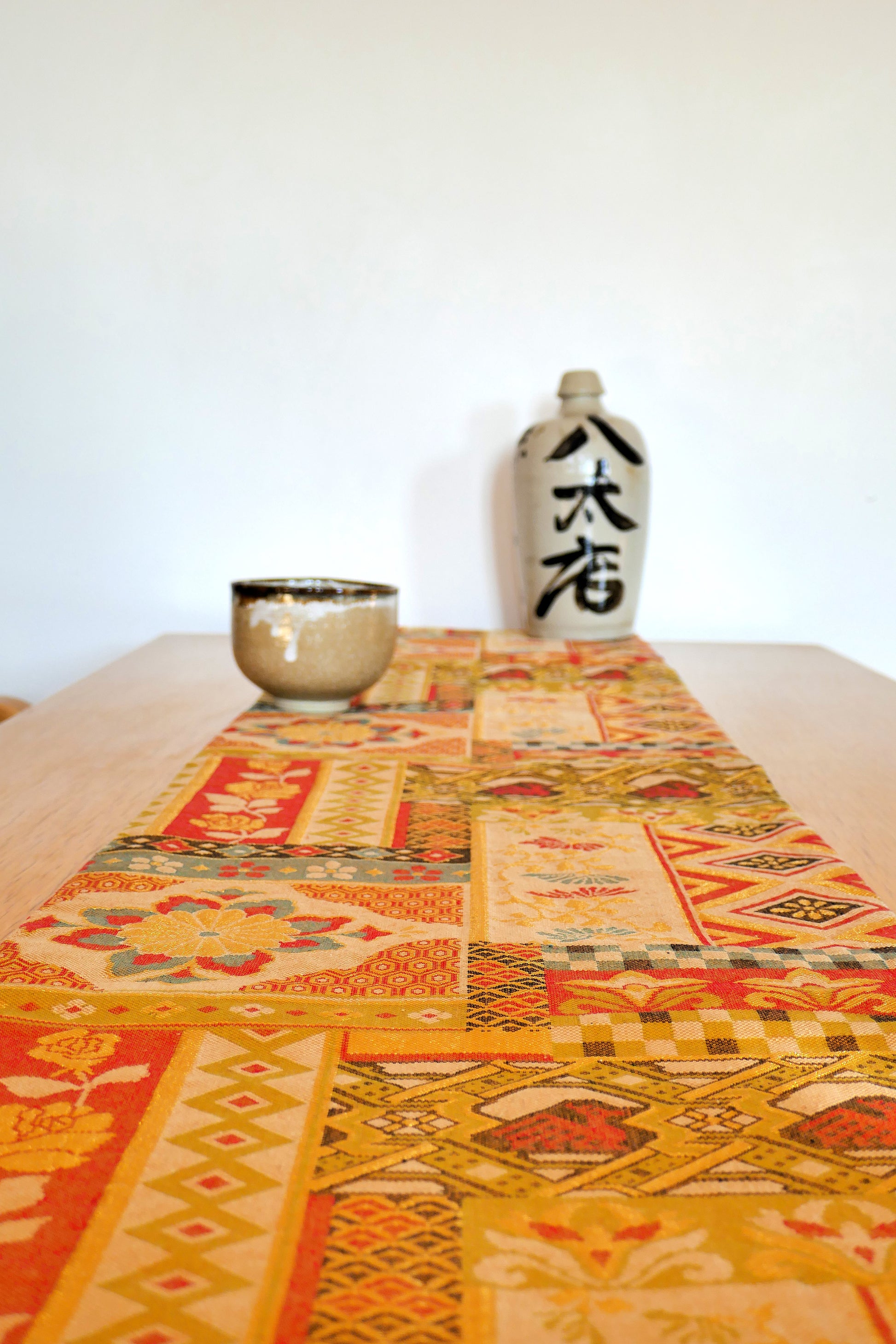 Mise en scène d’un obi ancien japonais en soie à motifs colorés sur table en bois