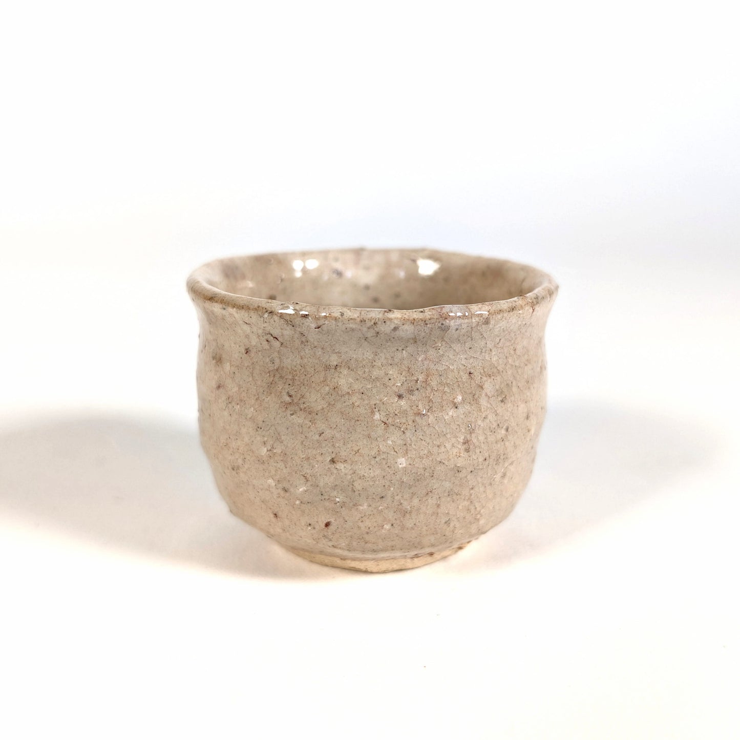 Profil d’une tasse à saké japonaise ochoko en céramique Hagi-yaki artisanale, détail de la surface craquelée