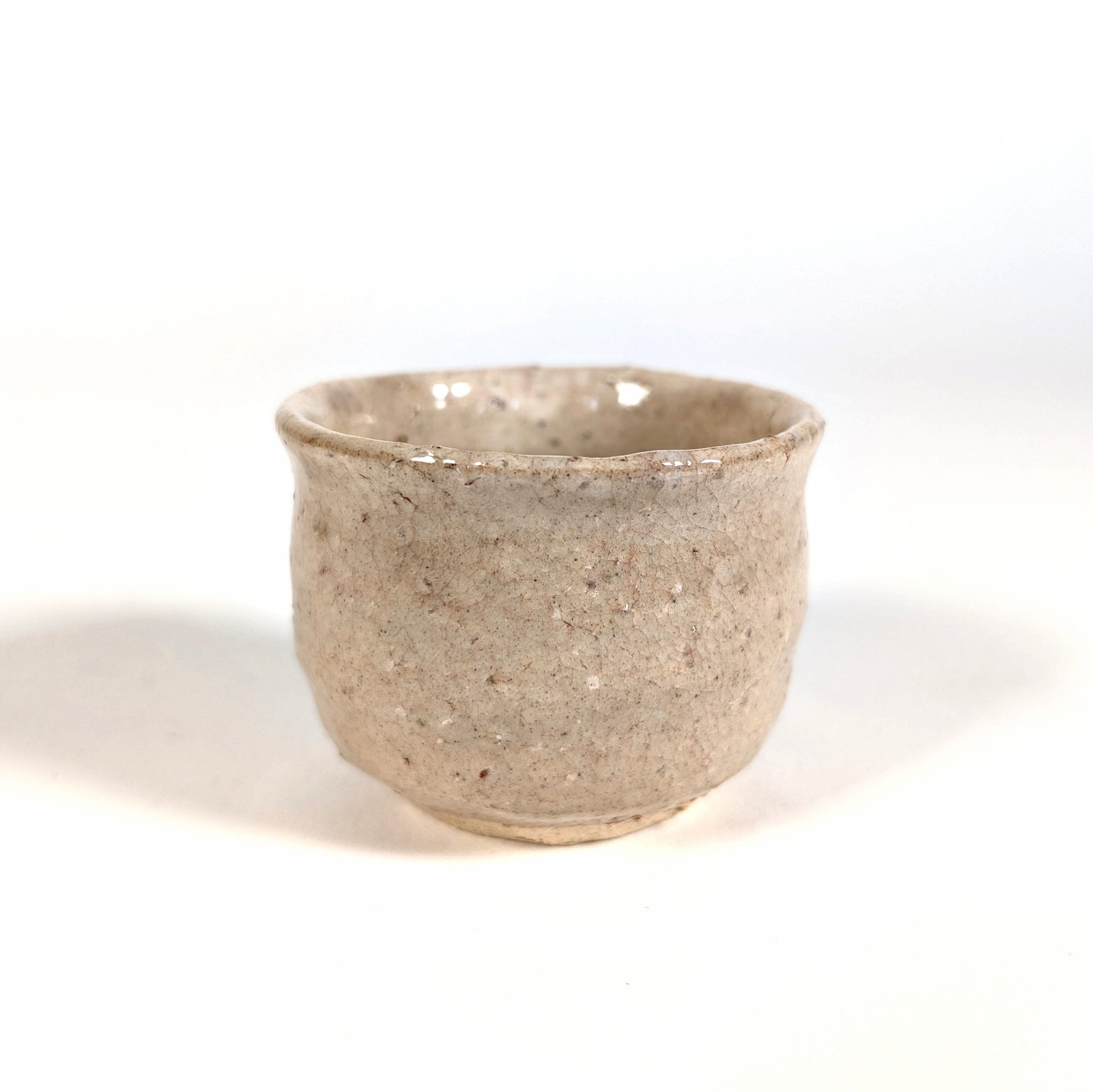 Profil d’une tasse à saké japonaise ochoko en céramique Hagi-yaki artisanale, détail de la surface craquelée