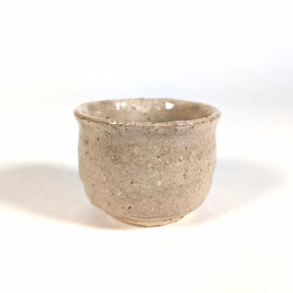 Profil d’une tasse à saké japonaise ochoko en céramique Hagi-yaki artisanale, détail de la surface craquelée
