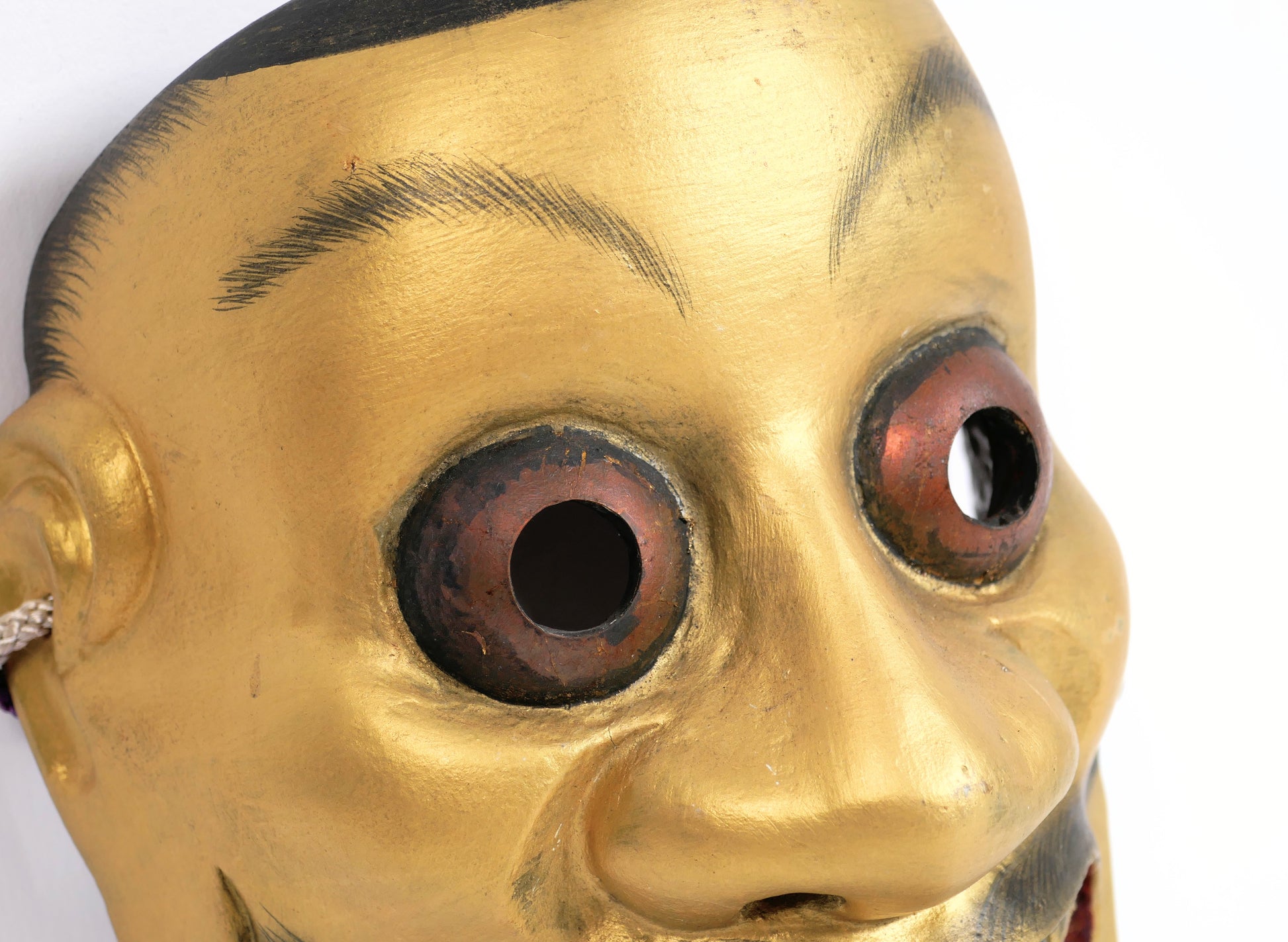 Détail des grands yeux saillants d’un masque Noh Ōtobide japonais en bois peint
