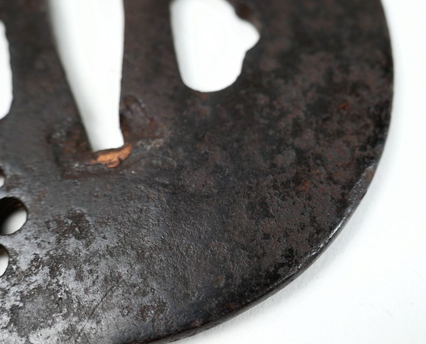 Macro de la patine ancienne du fer et du sekigane en cuivre autour du nakago-ana d’une tsuba japonaise antique.