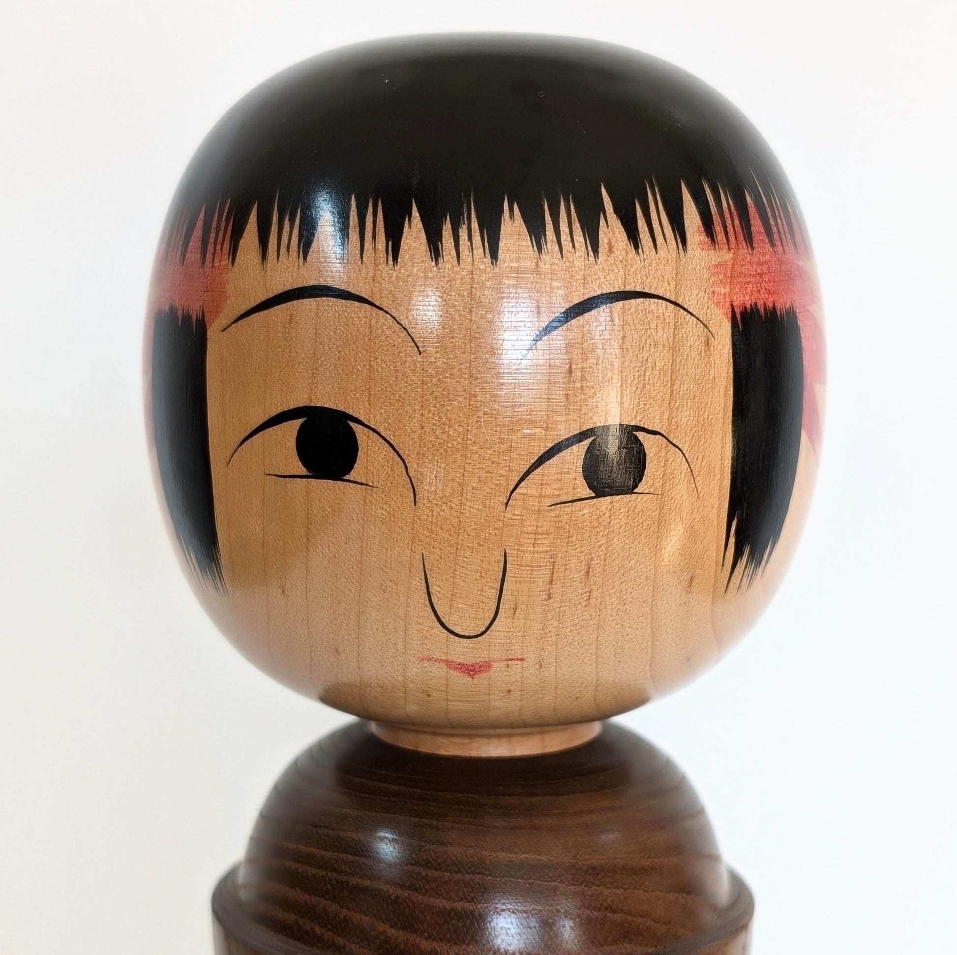Visage peint à la main d'une kokeshi Oshin par Mamoru Izu, expression douce et stylisée
