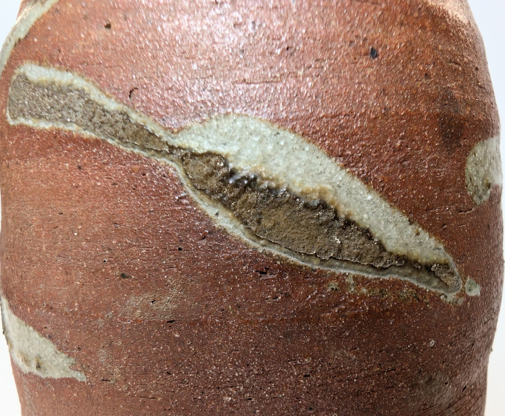 Gros plan sur la surface vitrifiée de la Tokkuri, montrant le bidoro, effet de cendre fondue typique des poteries yakishime japonaises.