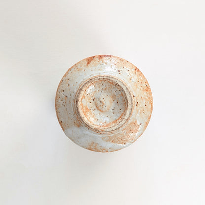 Dessous d'une tasse japonaise en céramique Shino, avec pied circulaire et traces de façonnage au tour.