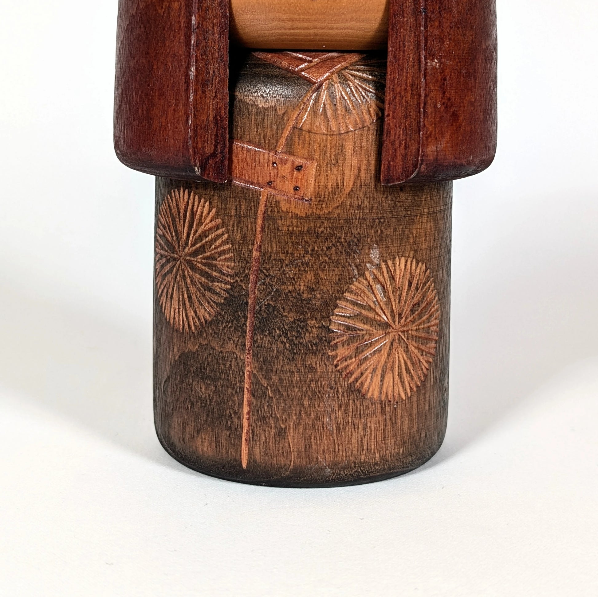 Détail du buste d’une poupée japonaise en bois, kokeshi sōsaku avec motifs gravés inspirés du kimono traditionnel