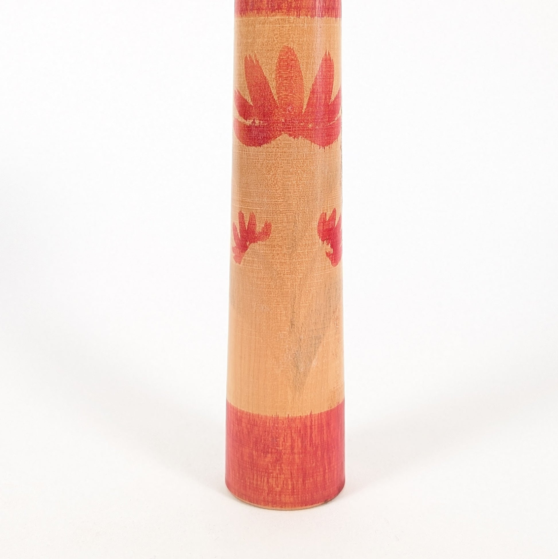 Détail du corps d’une poupée japonaise en bois, kokeshi Tsuchiyu avec motifs floraux rouges et patine vintage