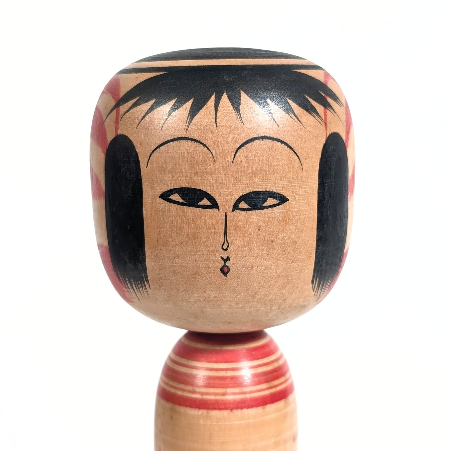 Gros plan du visage d’une poupée japonaise kokeshi en bois réalisée par l’artisan Yasuaki Katō.