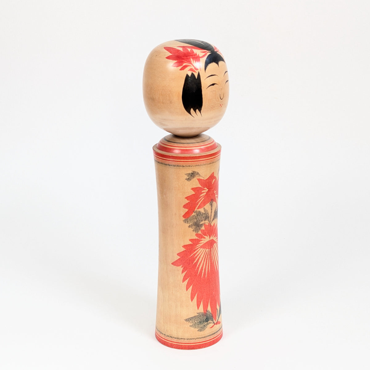 Poupée japonaise en bois de tradition Naruko vue de trois-quarts, kokeshi artisanale d’Okazaki Seishi au décor floral rouge.