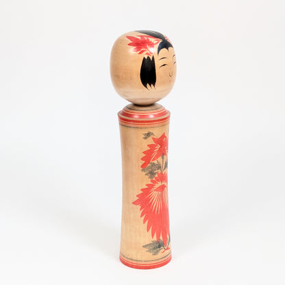Poupée japonaise en bois de tradition Naruko vue de trois-quarts, kokeshi artisanale d’Okazaki Seishi au décor floral rouge.